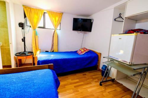 a bedroom with a blue bed and a window at Hostal Pampaloja Antof in Antofagasta
