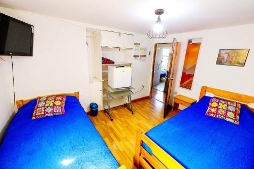 a bedroom with two beds and a desk and a tv at Hostal Pampaloja Antof in Antofagasta