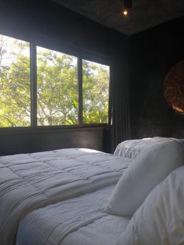 two beds in a bedroom with a window at Casa Vive Bacalar in Bacalar