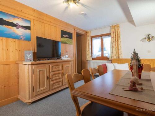 a dining room with a table and a flat screen tv at Holiday Apartment in Mittelberg with Wifi in Mittelberg