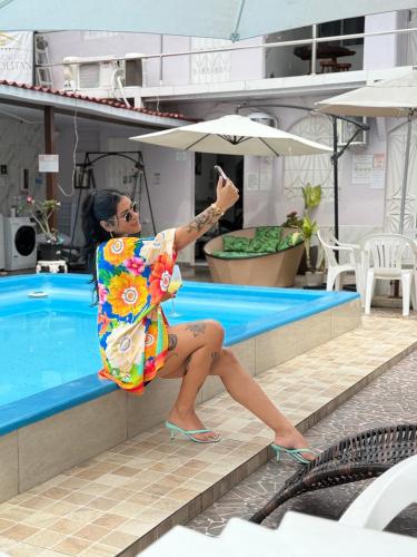 a woman sitting next to a swimming pool at Residencial Napolitan in Manaus