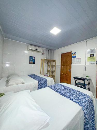 a room with three beds in a room with a door at Residencial Napolitan in Manaus
