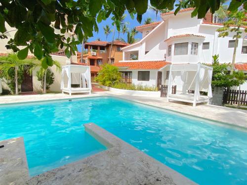 a swimming pool in front of a house at LAS PALMAS - DELUXE VILLAS and SUITES - playa LOS CORALES in Punta Cana
