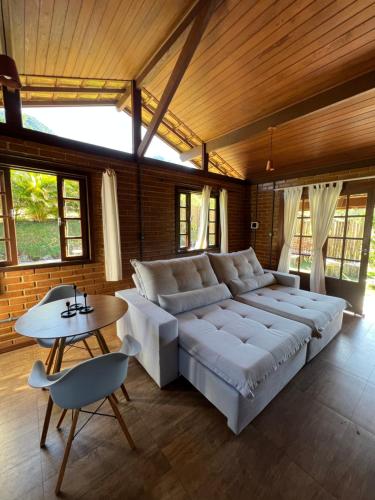 Cama blanca grande en habitación con mesa en Cactus Chalés & Cabanas em lumiar, en Lumiar
