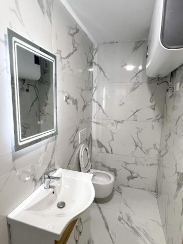 a white bathroom with a sink and a toilet at Villa Osmani in Shkodër