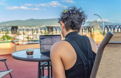 a woman sitting at a table with a laptop at Casa Mayahuel in Oaxaca City