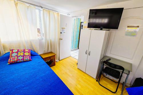 a bedroom with a bed and a tv on the wall at Hostal Pampaloja Antof in Antofagasta
