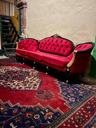 a red couch sitting in a room with a rug at Hotel Casa Rosario in San Miguel de Allende