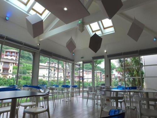une salle à manger avec tables, chaises et fenêtres dans l'établissement Apartment in Urrugne with Ocean Views, à Socoa