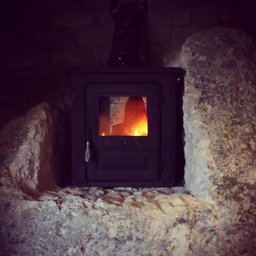 a stove in the snow with a fire in it at Black Birds Cabins Creel in Creel