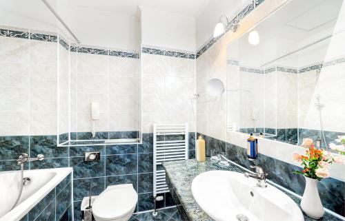 a bathroom with a sink and a toilet and a tub at Grand Hotel Praha in Tatranská Lomnica