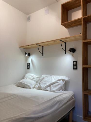 Cette chambre comprend un lit avec des draps blancs et des étagères en bois. dans l'établissement Chez papi fernand la villetta, à La Plagne Tarentaise