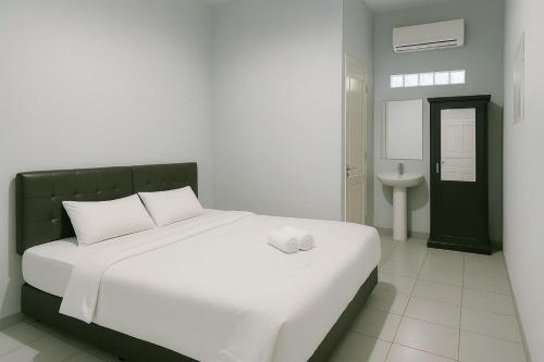 a bedroom with a large white bed and a sink at Elang House near Simpang Lima Tasikmalaya Mitra RedDoorz in Tasikmalaya