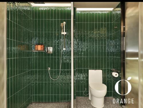 e bagno piastrellato verde con servizi igienici e doccia. di Orange Hotel Beijing Yizhuang Rongjing West Street a Pechino
