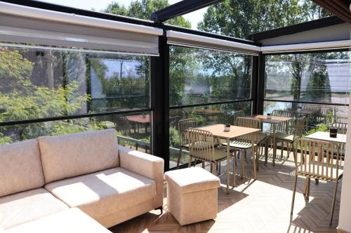 a screened in porch with a couch and tables and chairs at Villa Osmani in Shkodër
