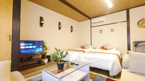 two beds in a room with a tv and a couch at 名鉄名古屋まで7分1棟貸し切り駐車場あり in Nishi-biwashima