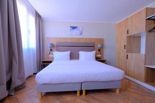a bedroom with a large bed with white sheets at Hôtel Appart Boumellit Centre Ville Jijel in Jijel
