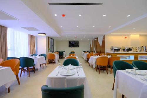 a dining room with white tables and green chairs at Hôtel Appart Boumellit Centre Ville Jijel in Jijel