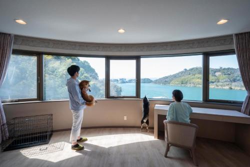 a man holding a teddy bear in front of a large window at Izumigo Lake Hamana Dog Paradise Hotel in Hamamatsu