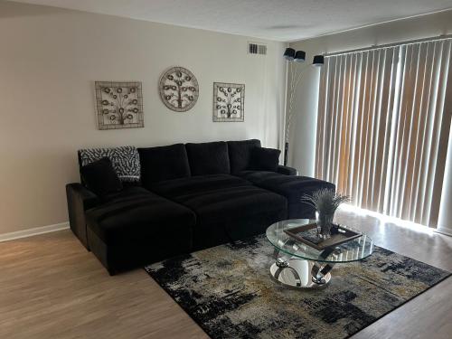 a living room with a black couch and a glass table at Sweet home in Indianapolis