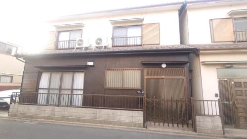 a brown and white house with a fence at 名鉄名古屋まで7分1棟貸し切り駐車場あり in Nishi-biwashima