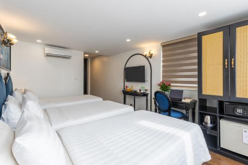 a hotel room with two beds and a desk at Hanoi House Hotel & Travel in Hanoi