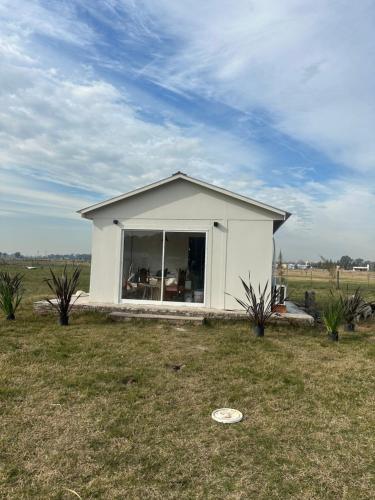 una pequeña casa blanca en medio de un campo en Epona, en Marcos Paz