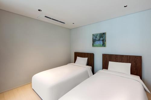 two beds in a room with white walls at NewCZ Haeundae Residence in Busan