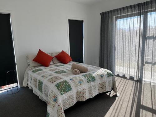 a bedroom with a bed with a blanket and a window at Jack Adamson Retreat in Twizel