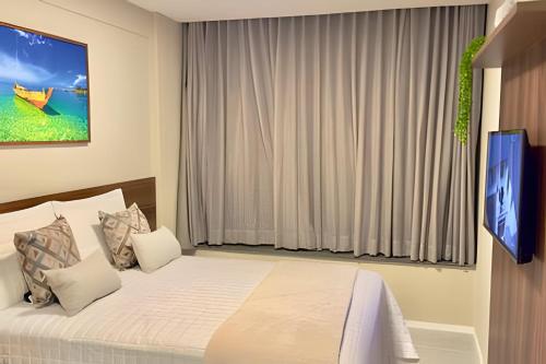 a bedroom with a bed with a television in it at Apartamento Pé na Areia Cond Alphaville Guarajuba in Camaçari
