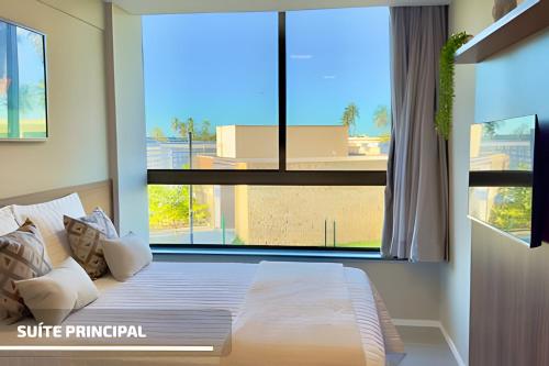 a bedroom with a bed with a large window at Apartamento Pé na Areia Cond Alphaville Guarajuba in Camaçari
