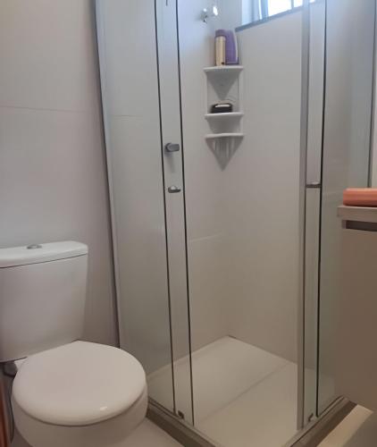 a bathroom with a toilet and a glass shower at Apartamento Pé na Areia Cond Alphaville Guarajuba in Camaçari