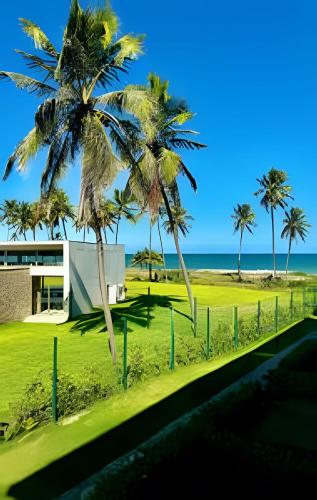 a view of the beach and palm trees at Apartamento Pé na Areia Cond Alphaville Guarajuba in Camaçari