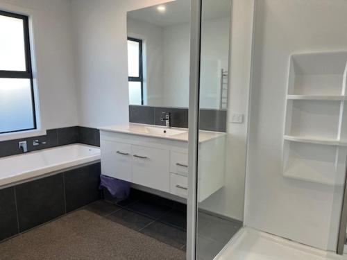 a bathroom with a sink and a tub and a mirror at Jack Adamson Retreat in Twizel