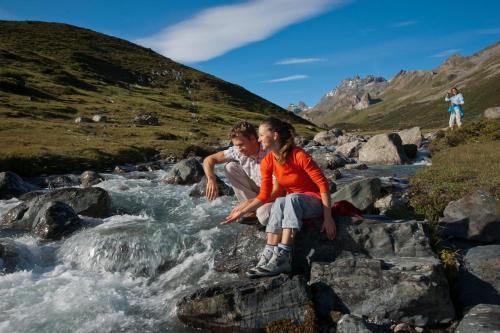 a woman and a boy are standing on rocks near a river at Alphotel Garni Salner in Ischgl