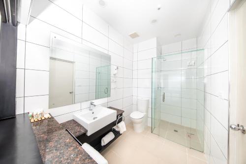 a white bathroom with a sink and a shower at Tanoa Waterfront Hotel in Lautoka