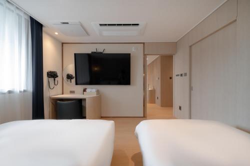a room with two beds and a flat screen tv at H avenue Incheon Seogu in Incheon