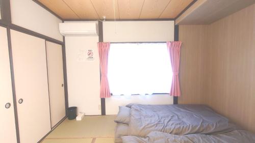 a small bedroom with a bed and a window at 名鉄名古屋まで7分1棟貸し切り駐車場あり in Nishi-biwashima