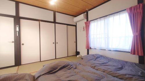 a bedroom with a bed and a window and cabinets at 名鉄名古屋まで7分1棟貸し切り駐車場あり in Nishi-biwashima
