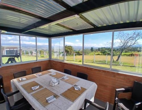 a dining room with a table and some windows at Finca Dulce María J&M Hospedaje Rural in Tunja