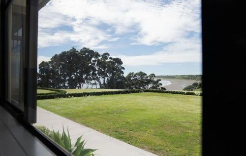 a window view of a field of grass and a road at Bay View Terrace Studio 4 in Tataraimaka