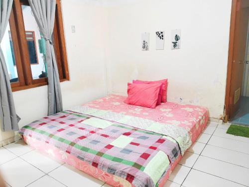 a bed in a room with a pink pillow on it at Homey Guesthouse Kertajaya (Syariah) in Surabaya