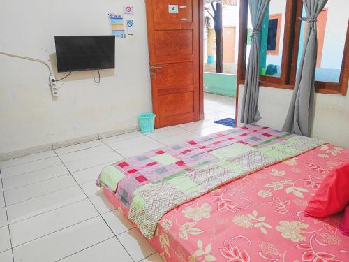 a bedroom with a bed and a tv on the wall at Homey Guesthouse Kertajaya (Syariah) in Surabaya