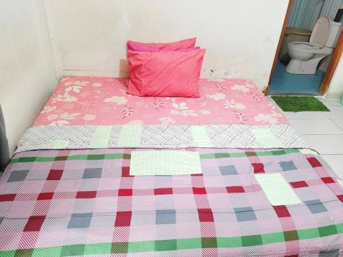 a bed with a pink pillow on top of it at Homey Guesthouse Kertajaya (Syariah) in Surabaya