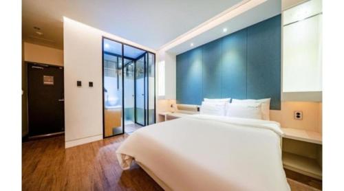 a bedroom with a large bed and a large window at Noel Business Hotel in Busan