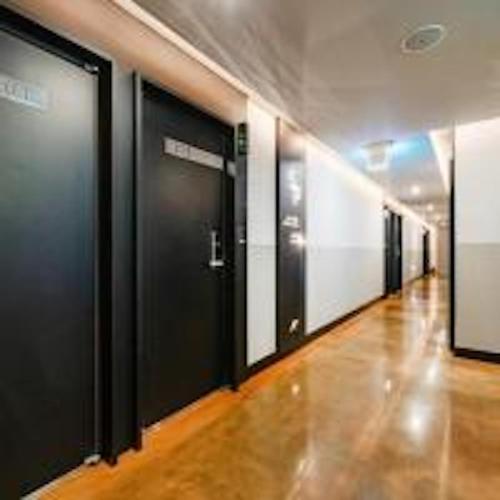 a hallway with black doors in a building at Noel Business Hotel in Busan