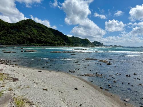 a beach with rocks in the water and mountains at 鴨川シーサイドヴィラ in Kamogawa