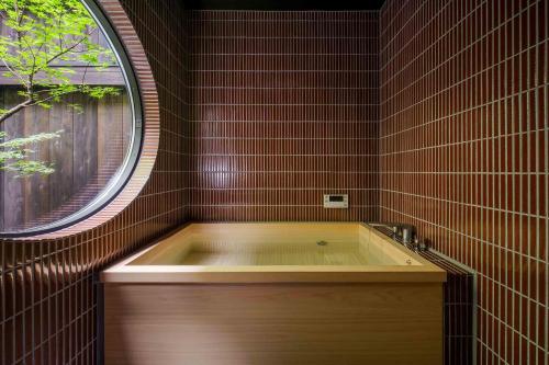 a bath tub in a bathroom with a round window at Nananohi Machiya House in Takayama