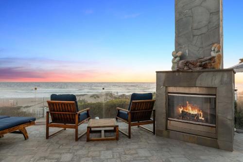 a fireplace on a patio with a view of the ocean at Malibu Dunes by Fieldtrip Expansive Hamptons-Style Estate w Private Beach Backyard in Malibu