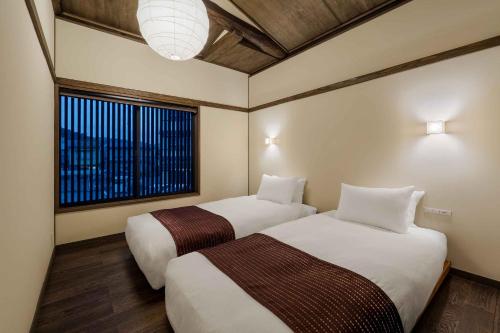 a hotel room with two beds and a window at Nananohi Machiya House in Takayama